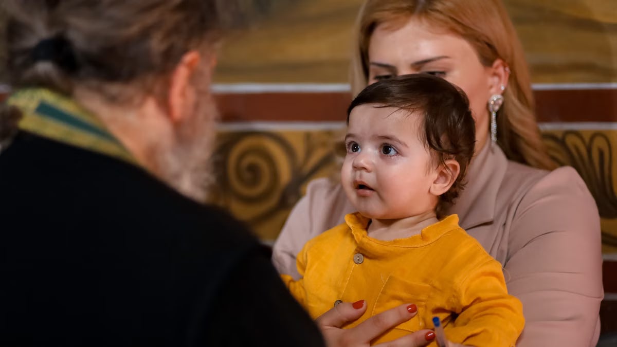A touching family moment during an indoor church event, showing a child held by a parent.